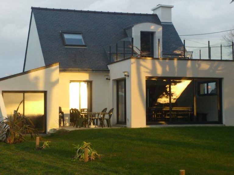 Maison contemporaine illuminée par la lumière chaude du soir avec terrasse.