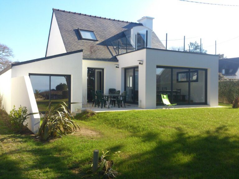 Vue extérieure d'une maison blanche moderne avec étage et grand jardin entretenu.